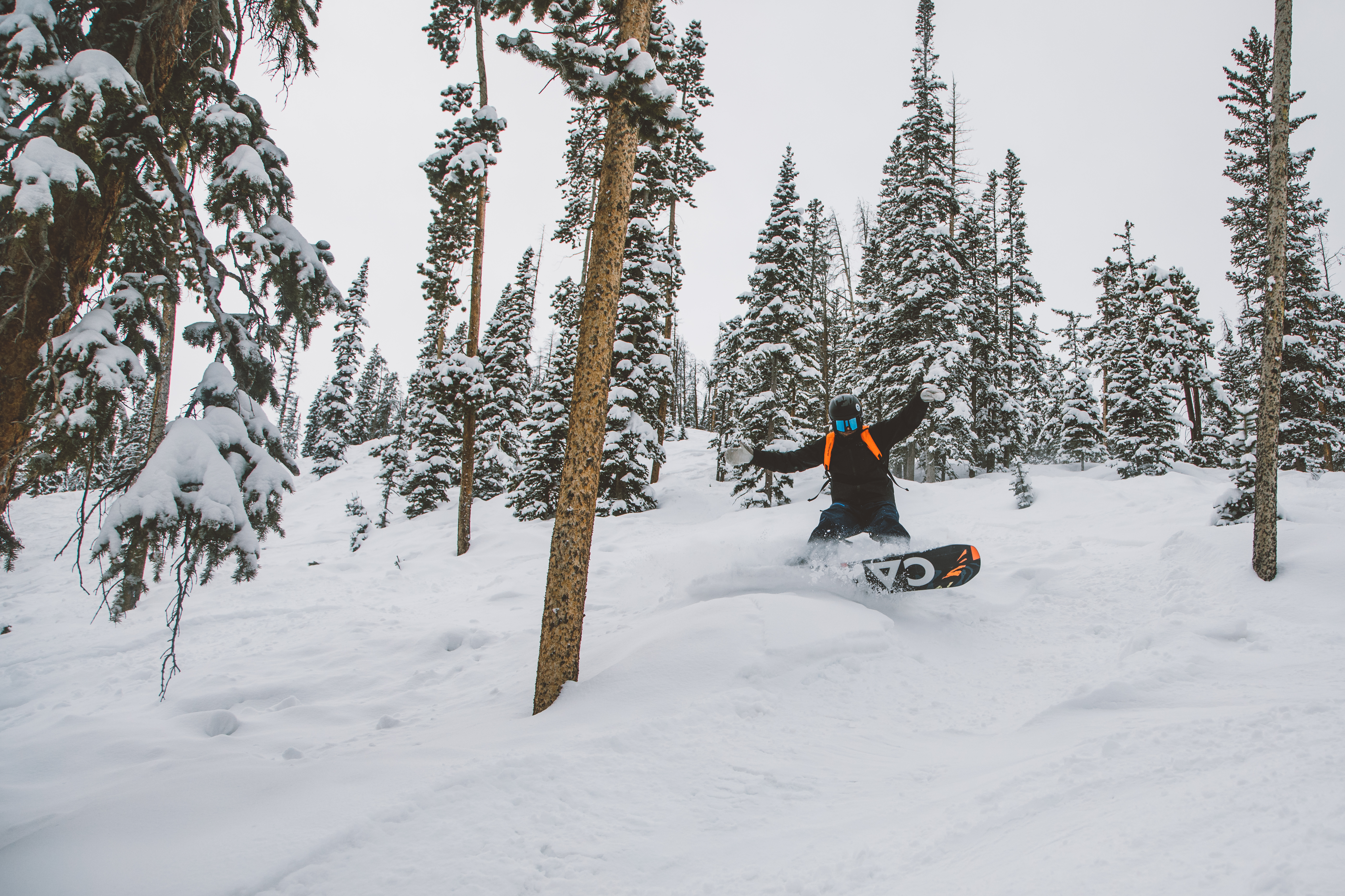 Man snowboarding down a hill on a board from Sun & Ski Sports